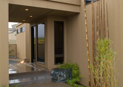Modern house entrance with a covered walkway and stone path after rainfall.