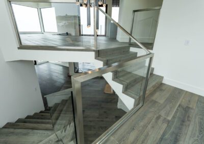 Modern interior with floating staircase and glass balustrades.