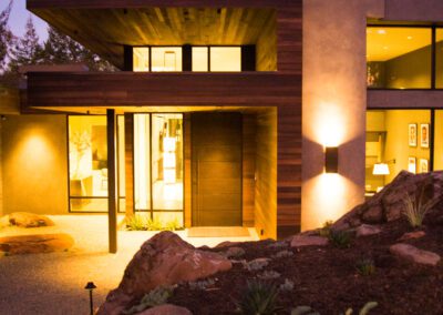 Modern house exterior illuminated at twilight with warm interior lighting and landscaped garden.