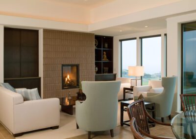 A contemporary living room at dusk with a lit fireplace, modern furnishings, and sliding glass doors.