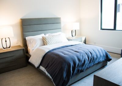 Modern bedroom with a neatly made bed, two bedside tables, and matching lamps.