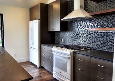 Modern kitchen interior featuring stainless steel appliances, dark wood cabinets, and a hexagonal tile backsplash.