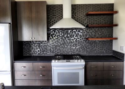 Modern kitchen with dark wood cabinetry, stainless steel appliances, and a mosaic tile backsplash.