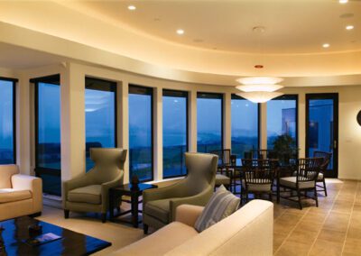 Modern living room with large windows offering a panoramic view of the landscape at dusk.