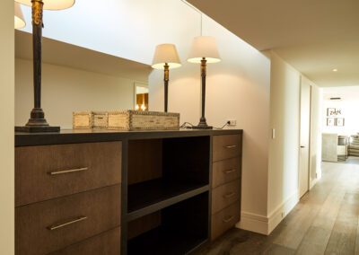 A warmly lit hallway featuring a built-in wooden desk with drawers and two table lamps.