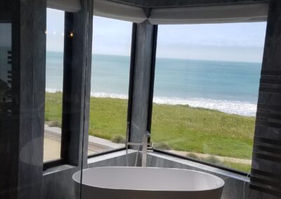 Modern bathroom with freestanding bathtub offering an ocean view.