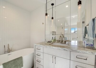 Modern bathroom with white tiling, marble countertop, and double vanity.