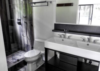Modern bathroom interior with a glass shower, white toilet, and double sink vanity.