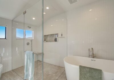 Modern bathroom interior with a freestanding tub, glass-enclosed shower, and a tiled wall.