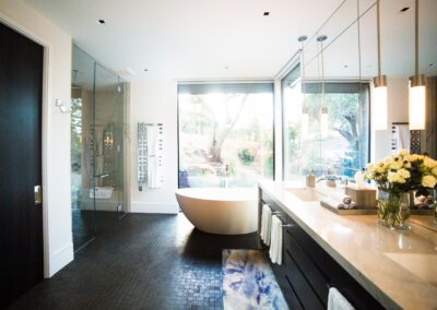 Bright, modern bathroom with a freestanding bathtub, glass shower, and a view of the outdoors.