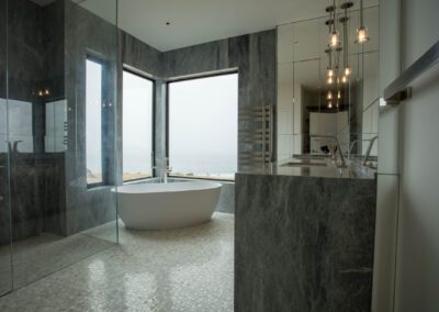 Modern bathroom with ocean view, featuring a freestanding tub and glass shower enclosure.