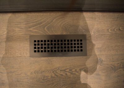 Ventilation register embedded in a wooden floor.