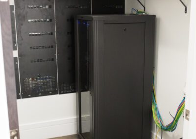 Network equipment cabinet with patch panels and switches in a server room.