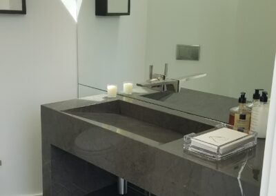 A modern bathroom with a dark stone countertop sink, wall-mounted faucet, and minimalist decor.