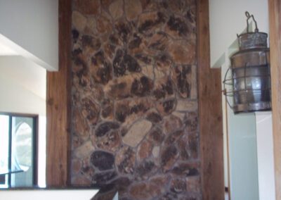 Before renovation: a room with stone wall accent and wooden beams.
